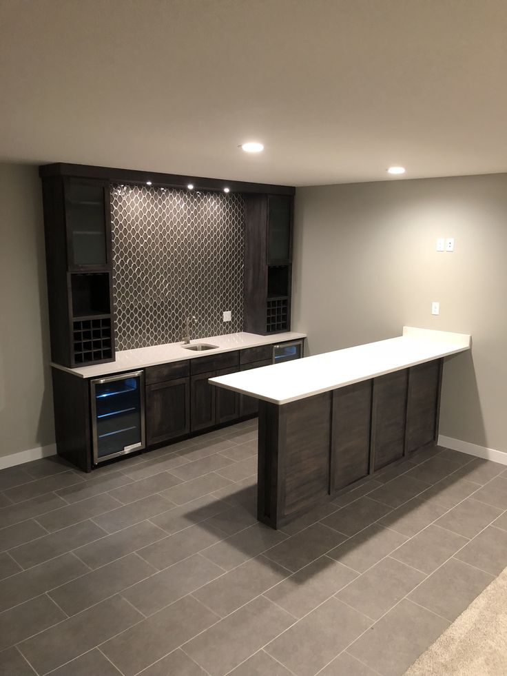 an empty kitchen with dark wood cabinets and white counter tops, along with tile flooring