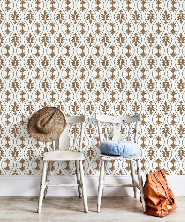 two chairs with hats on them in front of a wallpapered background that looks like an ornament