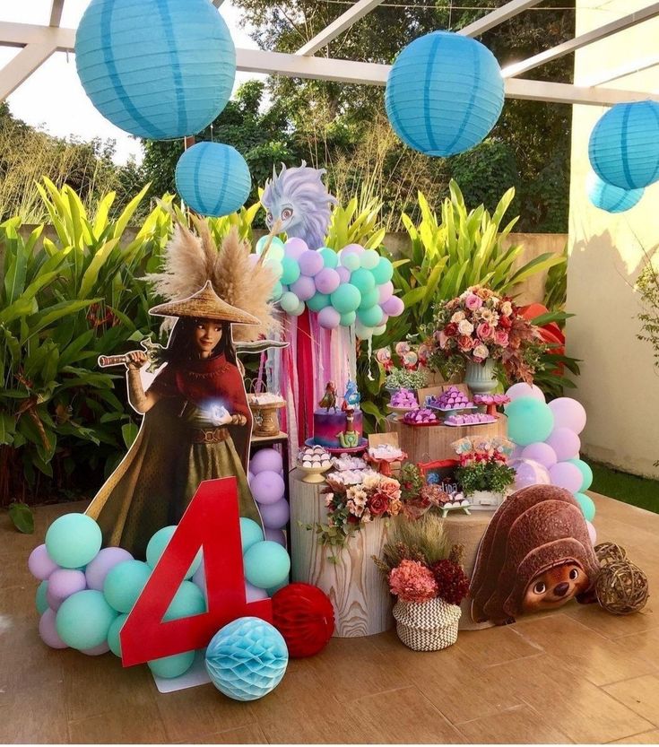 a table topped with balloons and decorations next to a number four sign in front of some plants