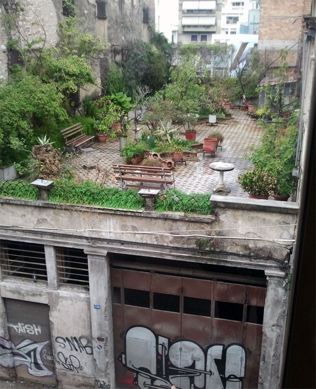 an old building with lots of plants growing on it's roof and some benches in the middle