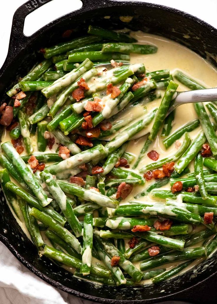 asparagus with bacon and cream sauce in a cast iron skillet on a white cloth