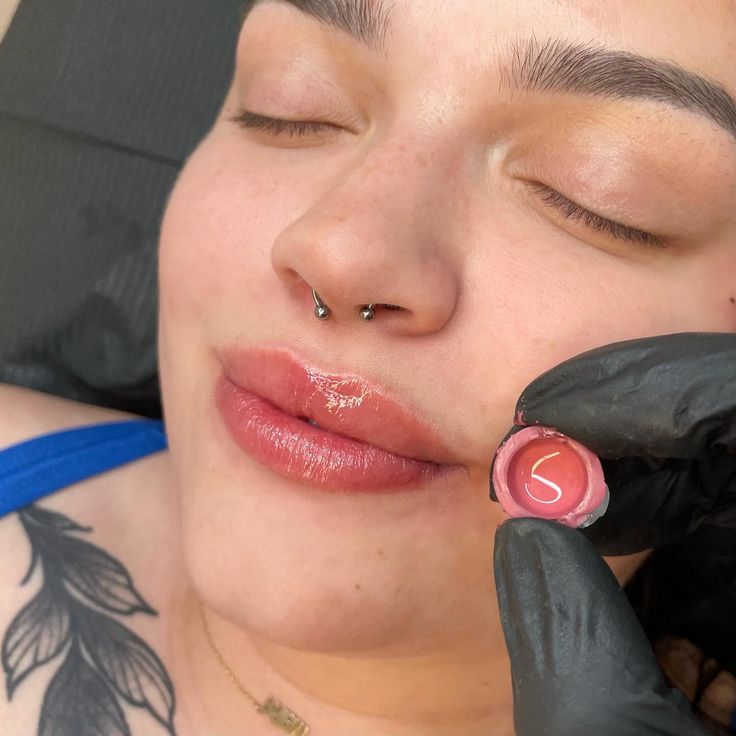 a woman getting her nose pierced by a tattoo artist