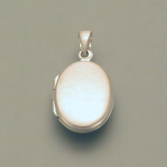 This little silver pendant has it literally “in itself”. It is a small medallion that you can open on the side and put a small photo or other souvenir inside. There would also be space inside or outside for a small engraving, but this is associated with a surcharge. If you would like to have the medallion engraved, just write to us. We will send you the medallion with either a polished or matt surface; if you don't specify it, the front would be matted and the back would be polished so that you Silver Sterling Silver Locket Necklace With Charms, Silver Medallion Locket Necklace With Polished Finish, Nickel-free Silver Oval Locket Necklace, Silver Oval Pendant Locket Necklace With Charms, Silver Locket Necklace With Charms And Oval Pendant, Small Photos, Nickel Silver, Elegant Earrings, Gold Plated Silver