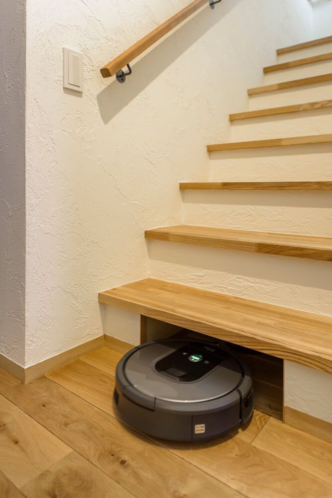 a roomba is sitting on the floor in front of some stairs and wooden steps