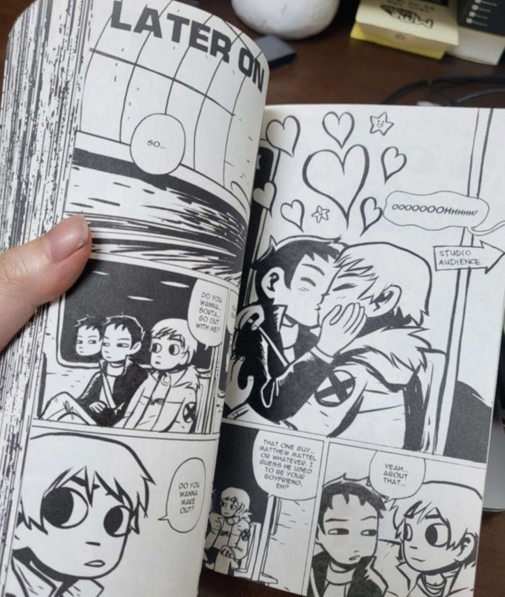 an open comic book with comics on the pages and hand holding it in front of them