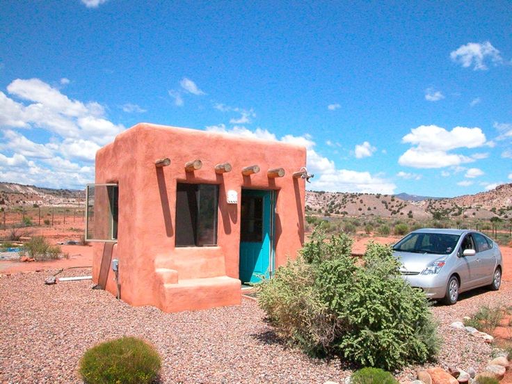 a car parked in front of a small adobe house