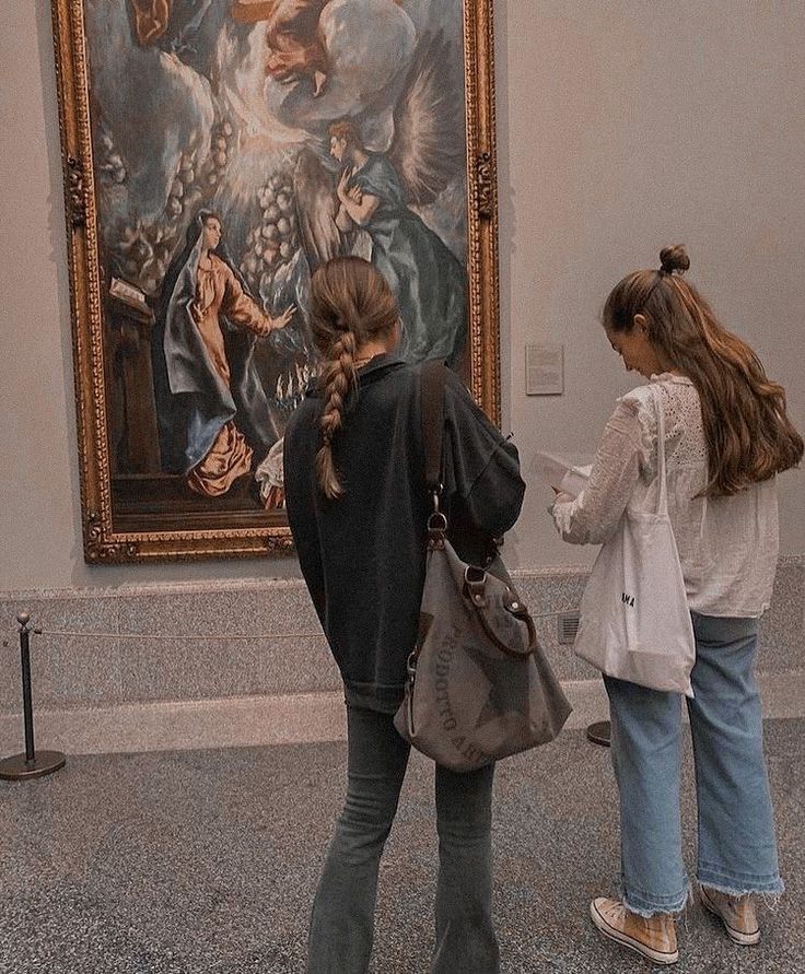 two women are standing in front of a painting