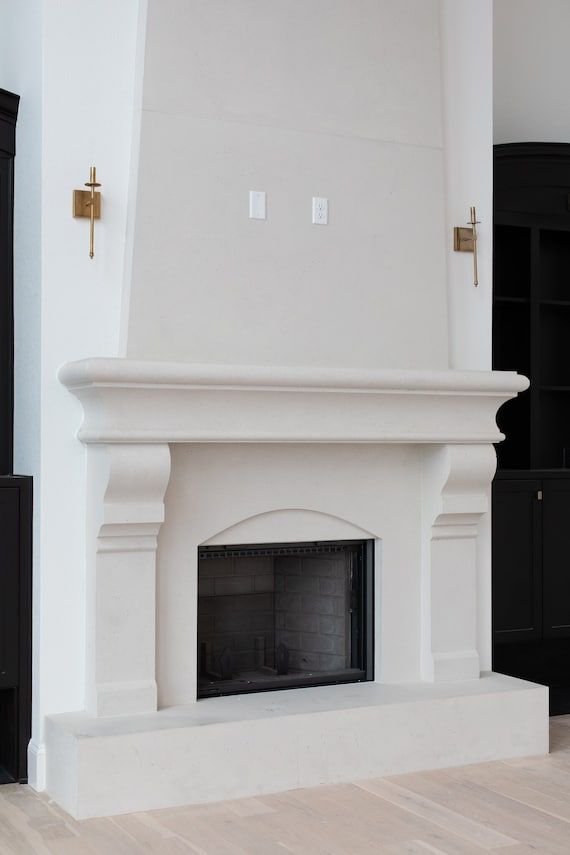 a white fireplace in a living room with black bookcases