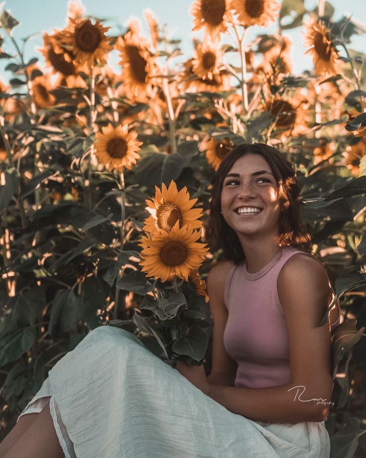 a woman sitting in the middle of a field of sunflowers