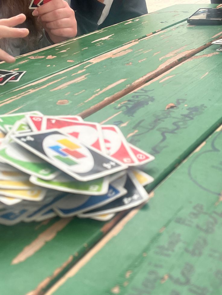 a person sitting at a green table with cards on it and their fingers pointing to them