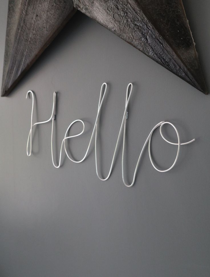 the word hello written in white string on a gray wall next to a wooden star