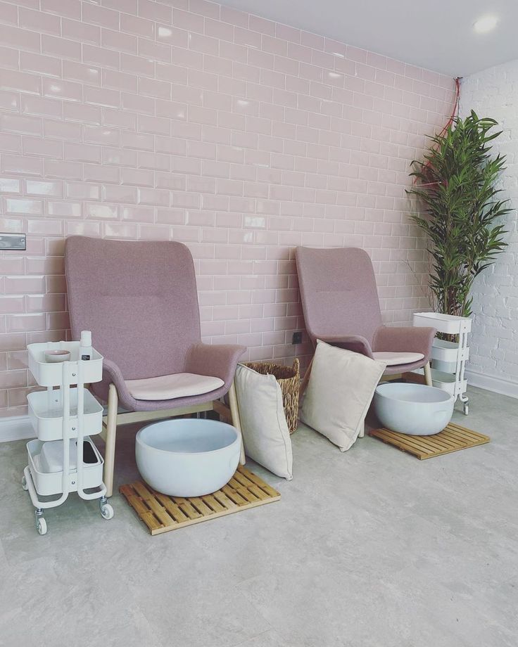 three chairs and two tables in front of a pink brick wall with plant on the floor