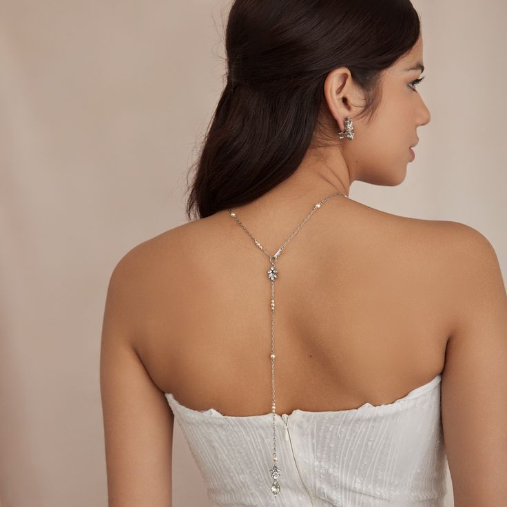 Dive into elegance with our Evangeline necklace, a delicate silver-tone metal chain necklace with dainty Czech glass pearls. This versatile necklace also creates the perfect drop design in back, accentuating your gown from all sides. All Ben-Amun jewelry is handcrafted and made to order in New York City, so please allow 7-14 business days for production before the ship date. Measurements: 26" L Delicate Silver Body Chain For Party, Silver Dainty Delicate Body Chain, Silver Dainty Delicate Chain Body Chain, Silver Body Chain With Clavicle Design For Wedding, Elegant Silver Teardrop Bridal Necklace, Elegant Silver Bridal Necklace With Teardrop Shape, Dainty Silver Clavicle Body Chain, Silver Delicate Chain Body Chain For Wedding, Elegant Silver Chain Body Chain