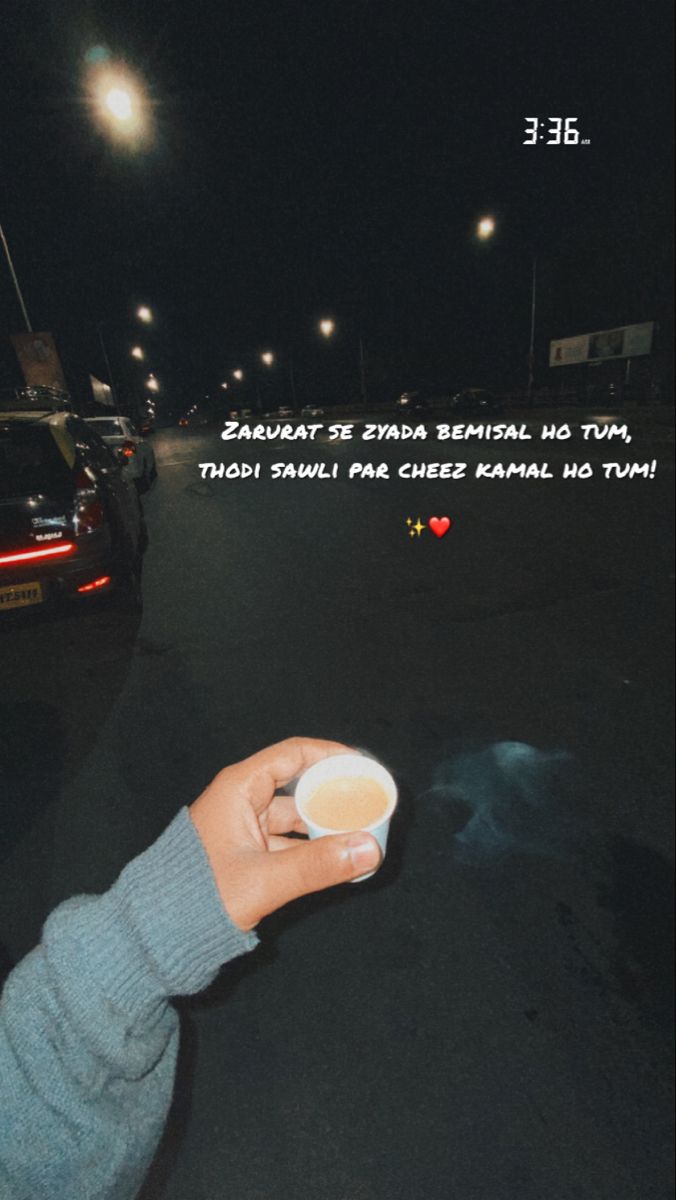 a person holding a cup in the middle of a street at night with an ad on it