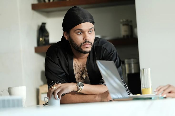 a man sitting at a table with a laptop in front of him and looking into the camera