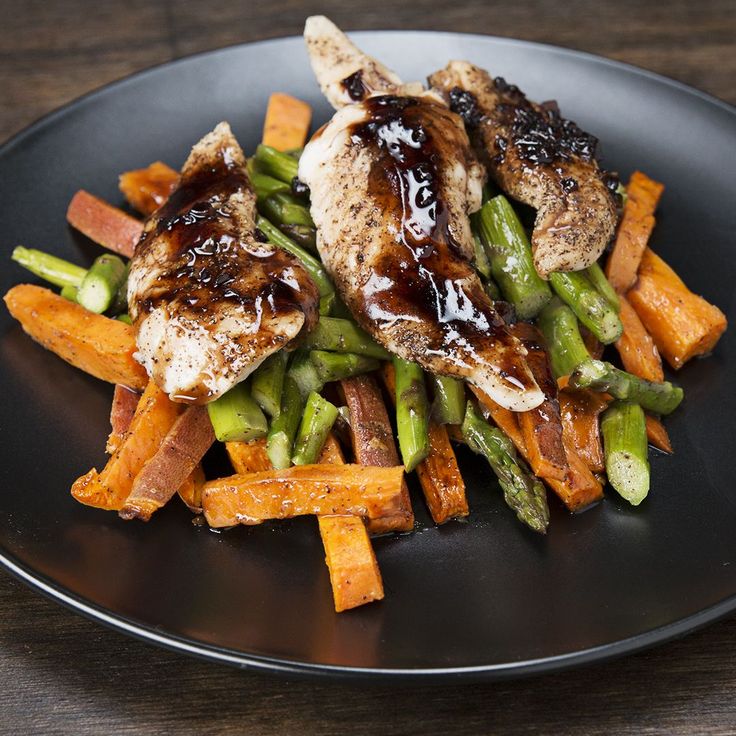 a plate with chicken, carrots and asparagus covered in bbq sauce