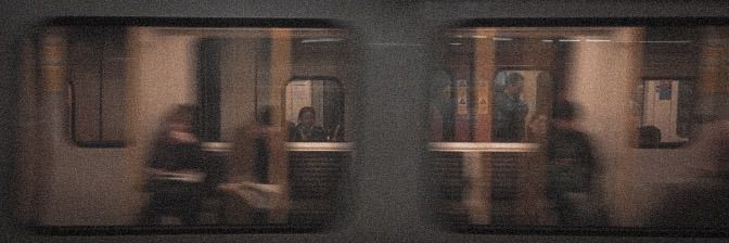 two people are standing on the train doors and one is looking at something in the distance