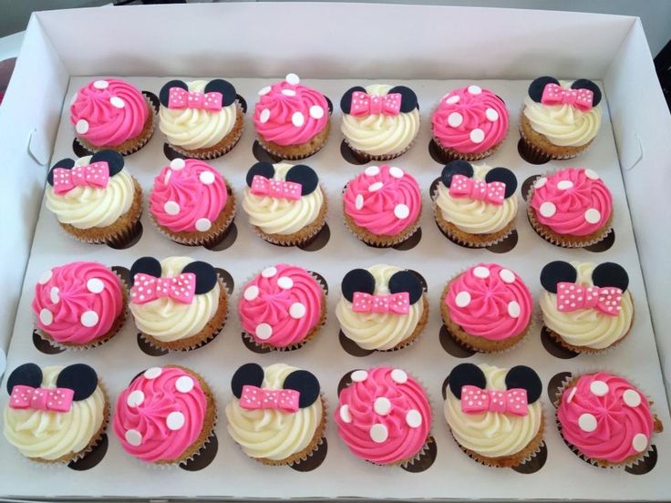 cupcakes with pink and white frosting decorated like minnie mouse ears are in a box