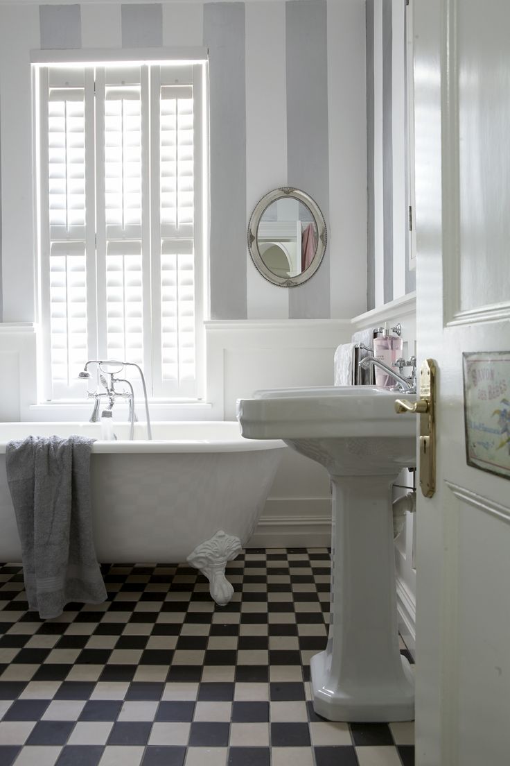 a white bath tub sitting next to a sink in a bathroom with black and white checkered flooring