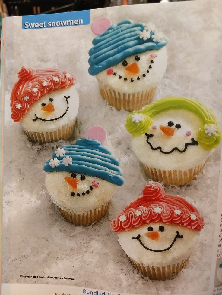 four cupcakes decorated with frosting and icing are sitting in the snow