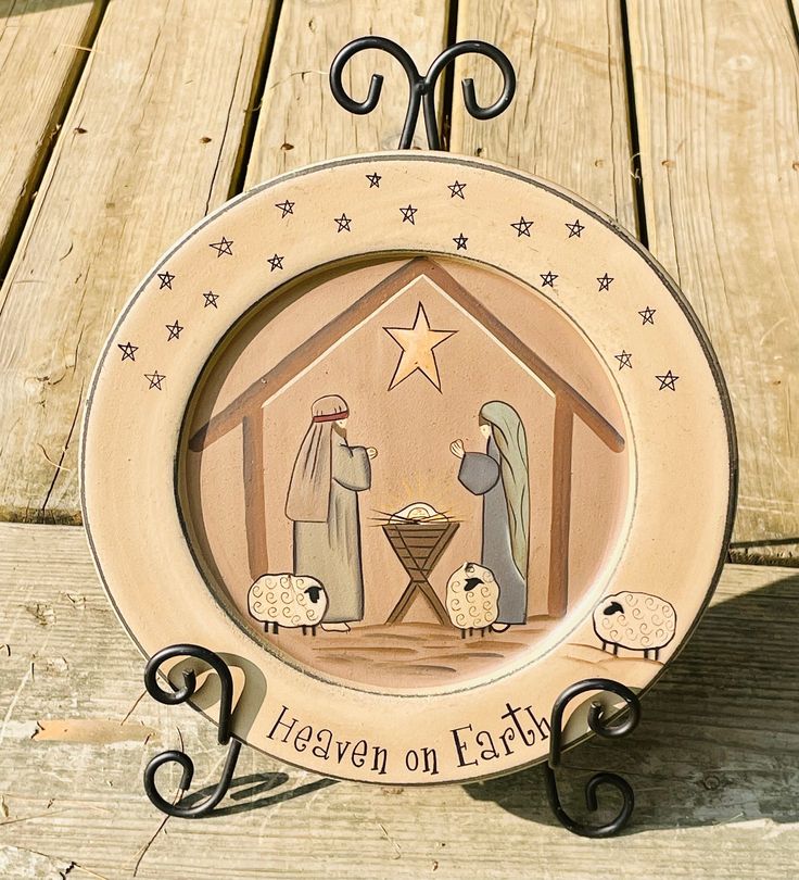 a nativity plate with the birth of jesus and baby jesus on it sitting on top of a wooden table