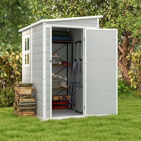 an outdoor storage shed with its doors open and shelves full of items on the grass