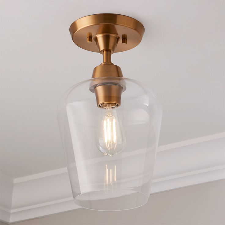 a light fixture with a clear glass dome on the ceiling and a gold metal frame