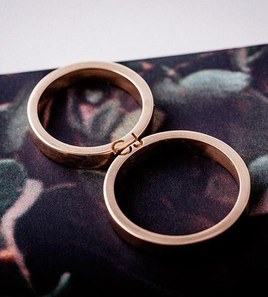 two gold rings sitting on top of a flowered cloth