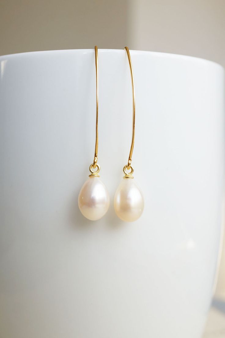 Long Gold Freshwater Pearl Drop Earrings, No. EGH056 :*About This Piece*: ♦︎ These matching, lustrous creamy freshwater pearl teardrops have hints of pink and are truly classy. They are hung on long gold plated sterling silver earrings. Due to the natural formation of these pearls, there will be slight variations in the color and shape of the pearls. ♦︎ Length - 1.7 in (43 mm) ♦︎ Width - .3 in (8 mm) ♦︎ All items from my shop are packaged in padded cardboard jewelry boxes. Custom gifting options Classic Long Drop Pearl Earrings With Ear Wire, Classic Drop Pearl Earrings For Everyday, Graceful Teardrop Pearl Charm Earrings, Minimalist Teardrop Pearl White Earrings, Pearl White Teardrop Pearl Charm Earrings, Everyday Teardrop Pearl Earrings, Cream Teardrop Earrings For Gift, Pearl White Teardrop Earrings For Everyday, Everyday Pearl White Teardrop Earrings