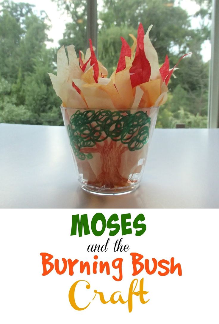 a cup filled with paper flowers on top of a table next to a sign that says moss and the burning bush craft