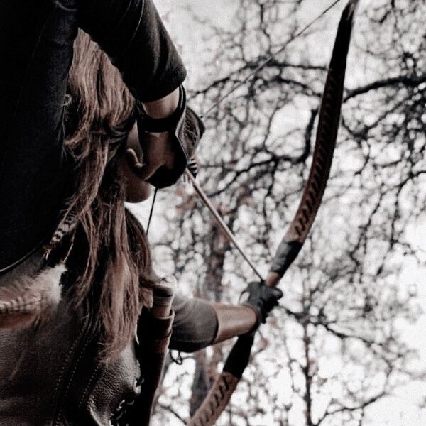 a woman is holding an arrow and aiming it in the air