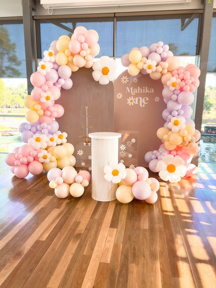 balloons are arranged in the shape of a wreath on a wooden floor next to a window