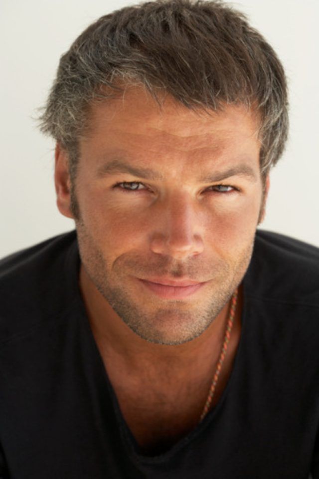 a close up of a person wearing a black shirt and looking at the camera with a serious look on his face