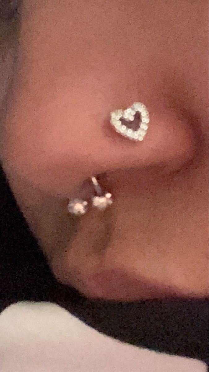 a close up of a person wearing ear piercings with two hearts on the side