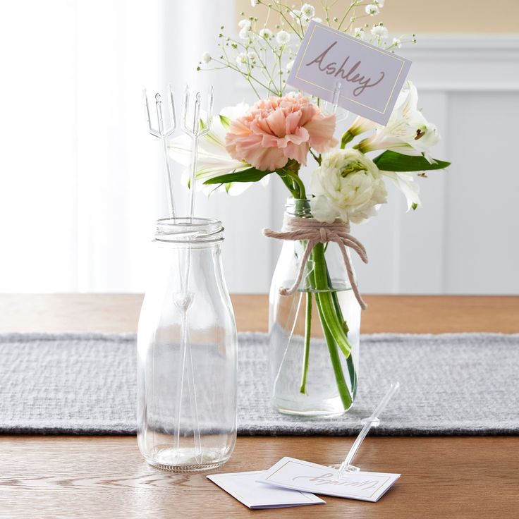 two vases filled with flowers on top of a wooden table next to a note