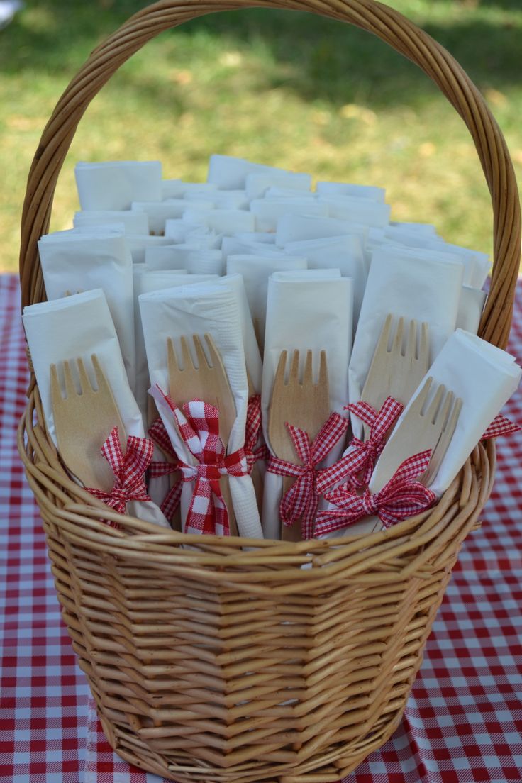 a wicker basket filled with forks and spoons on top of a checkered table cloth