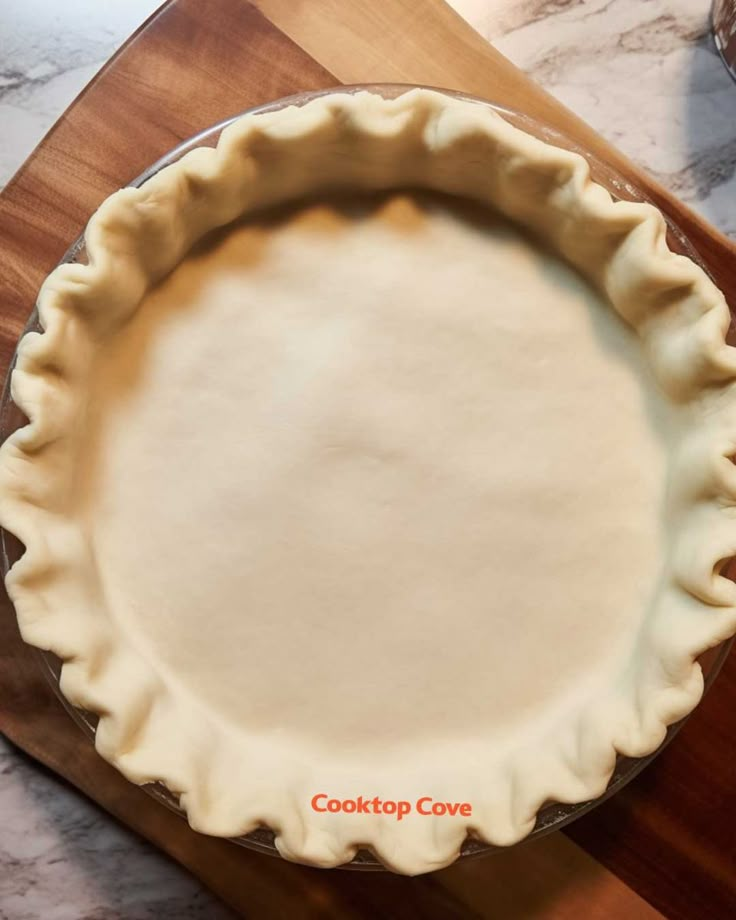 an uncooked pie crust sitting on top of a wooden cutting board