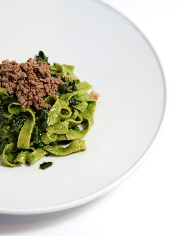 a white plate topped with pasta and meat covered in broccoli florets