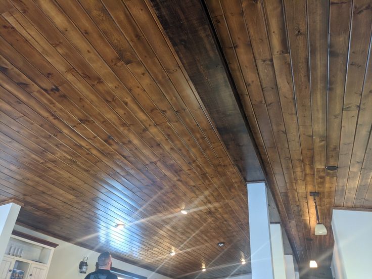 a man standing in the middle of a kitchen with wooden ceiling and beams on the ceiling