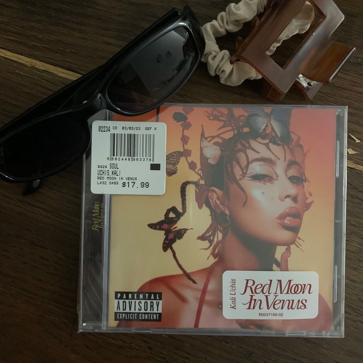 a pair of black sunglasses sitting on top of a wooden table next to a cd