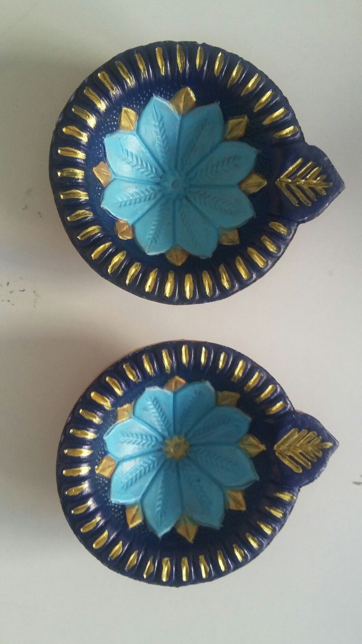 two decorative blue and gold dishes on a white table with one flower in the center