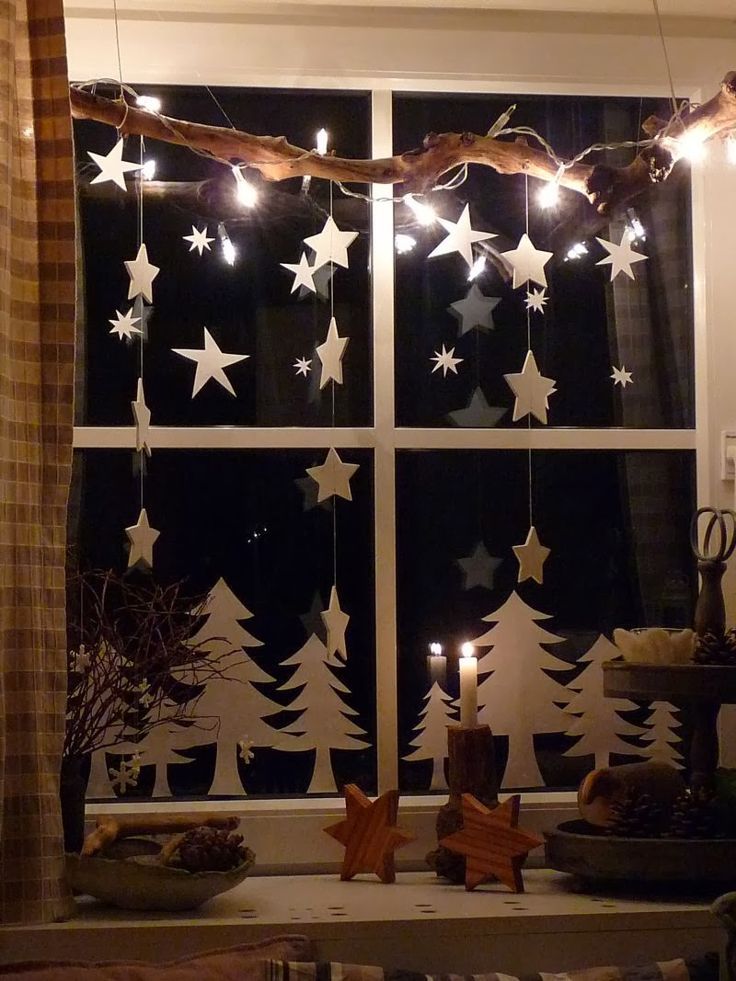 a window with christmas lights hanging from it's sides and stars on the windowsill