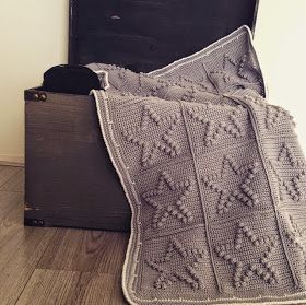 an old suitcase with a crocheted blanket on top