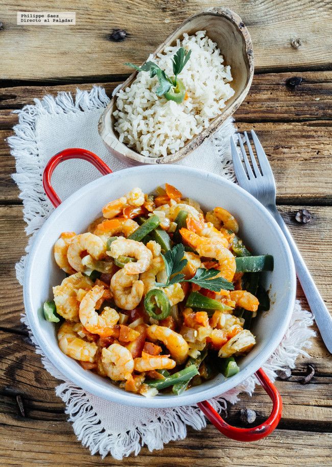 a white bowl filled with shrimp and rice next to a red handled utensil