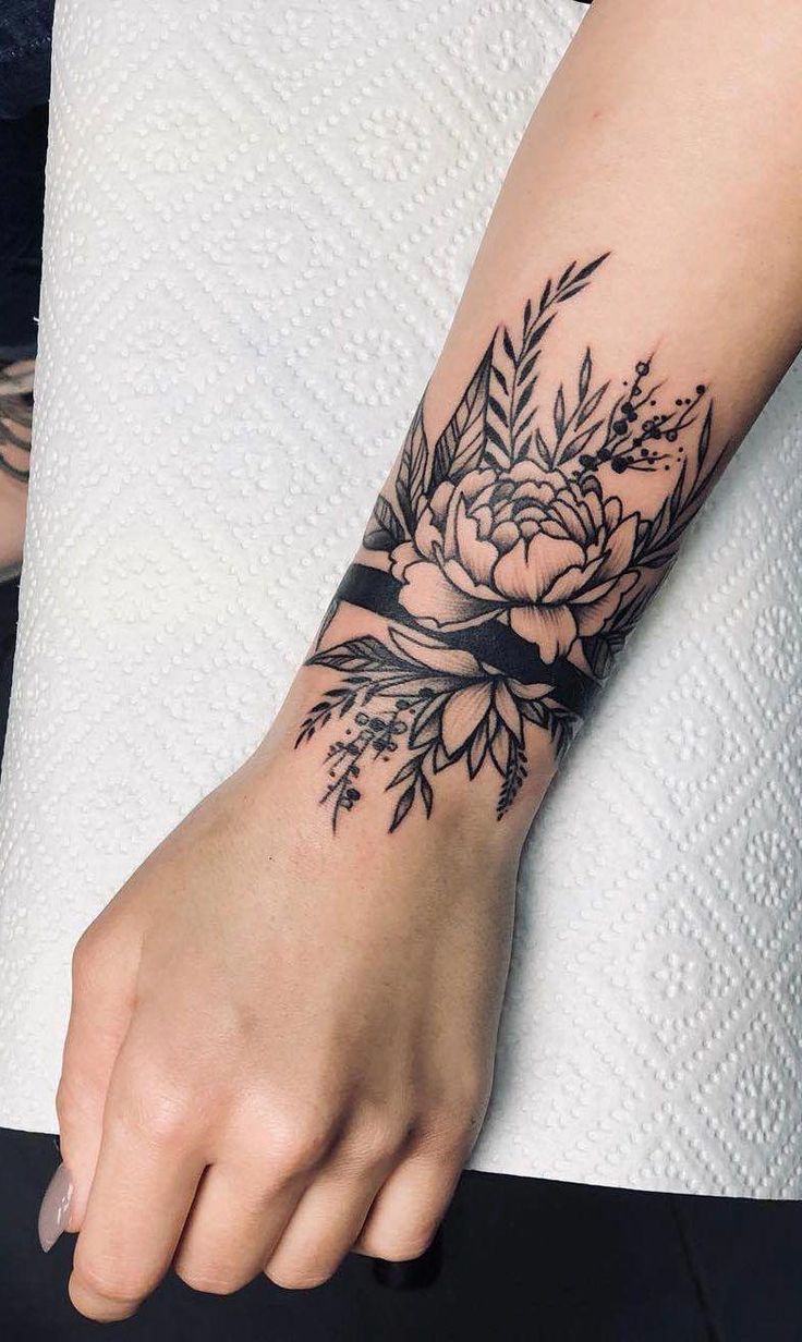 a woman's arm with a flower tattoo on it and a ring around the wrist