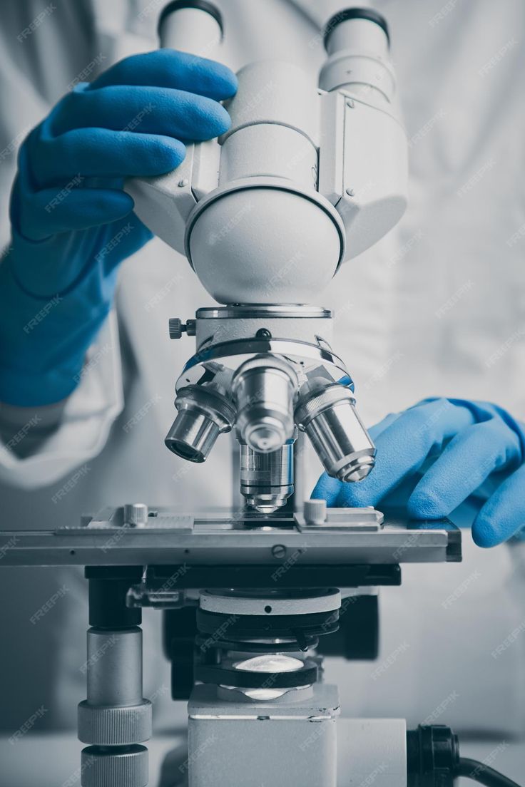 a person in blue gloves is looking through a microscope at something on top of it