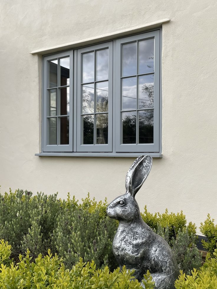 a metal rabbit statue sitting in front of a window