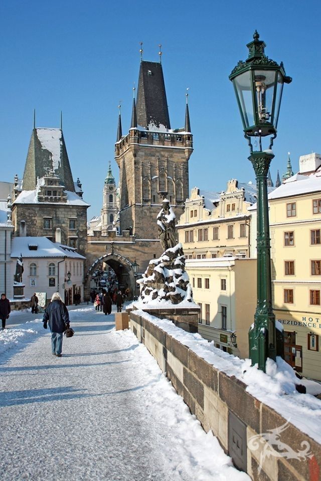 people are walking on the snow - covered walkway in front of some buildings and a street light