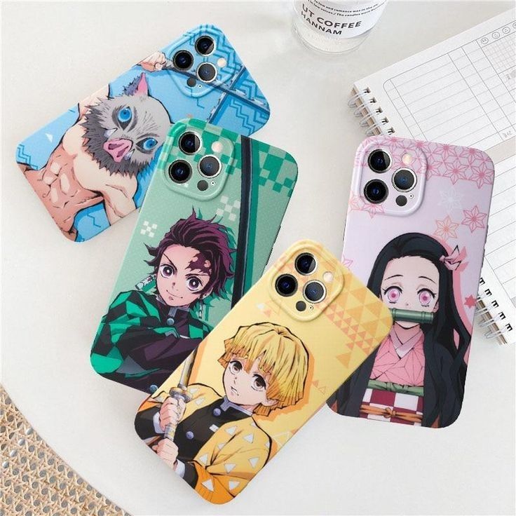 four phone cases with anime characters on them sitting next to a notepad and pen