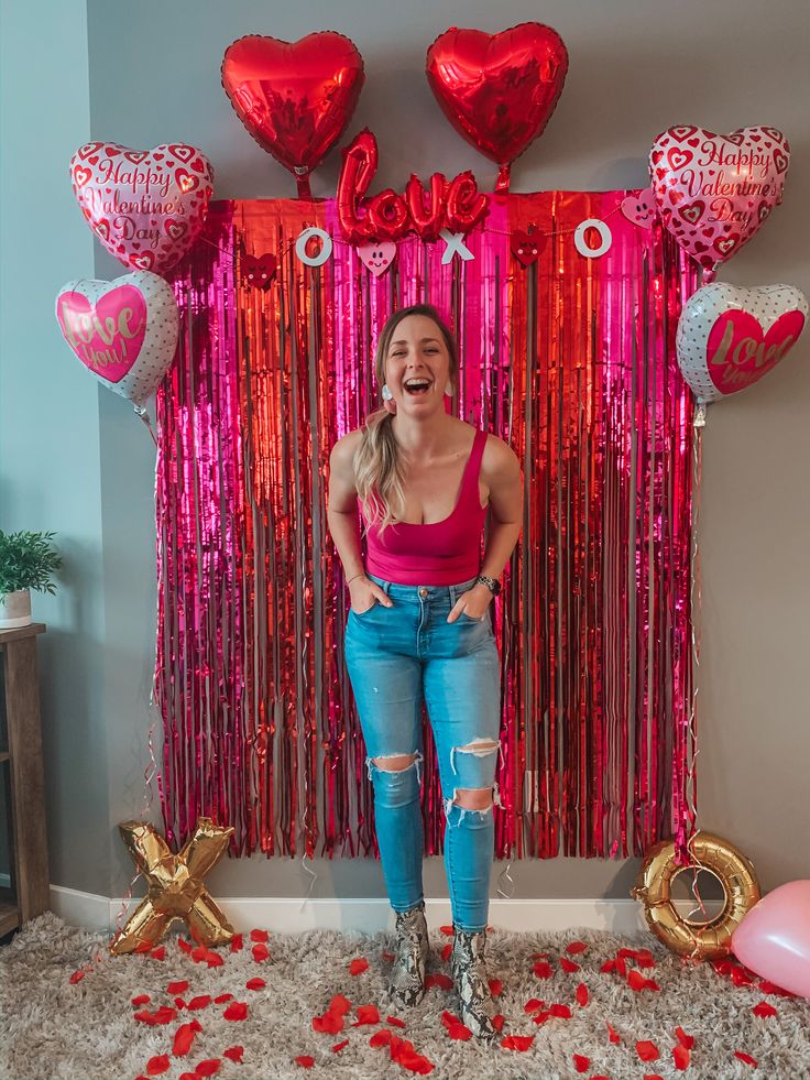 a woman standing in front of balloons and streamers with her hands on her hips